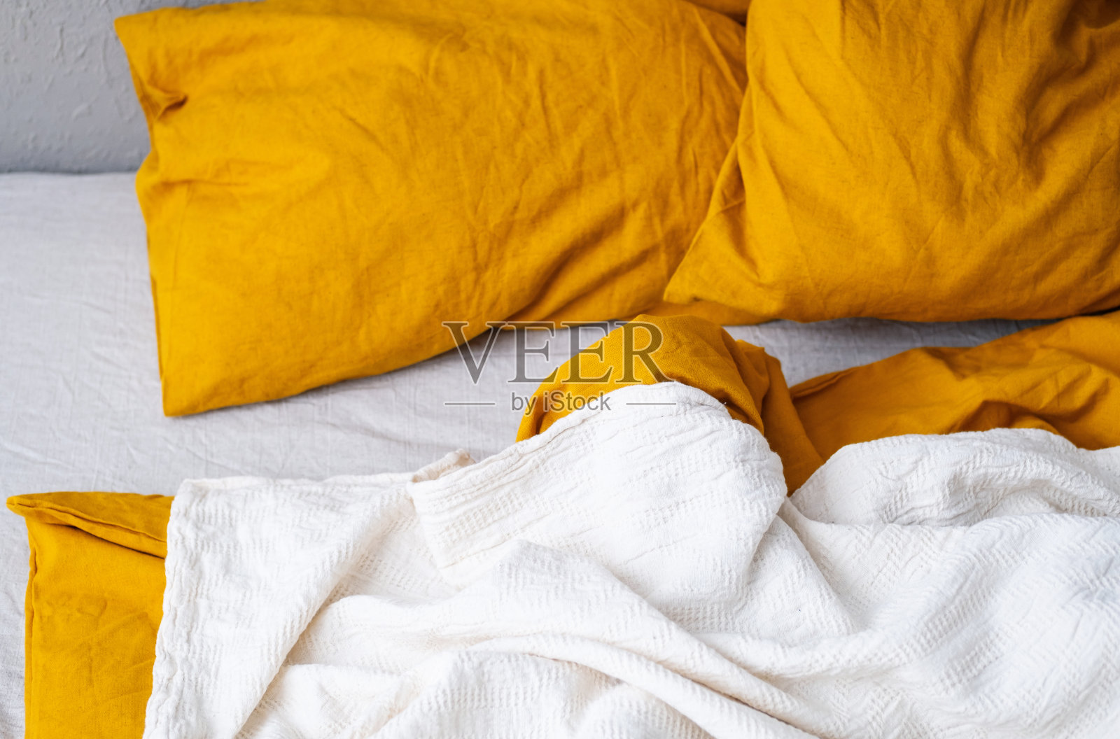 舒适的床，黄色的枕头和白色的毯子在现代卧室。照片摄影图片