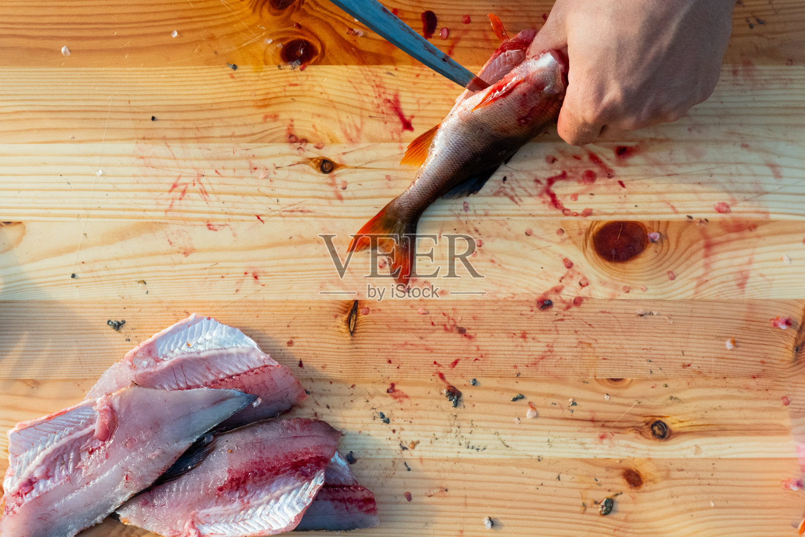 清洗和准备鱼。用刀在木板上做鱼片照片摄影图片