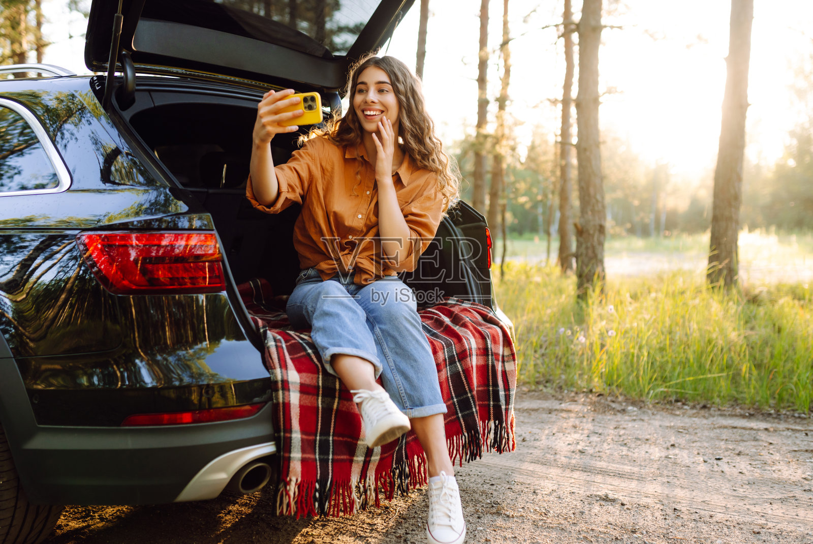美女在汽车后备箱里休息自拍。照片摄影图片