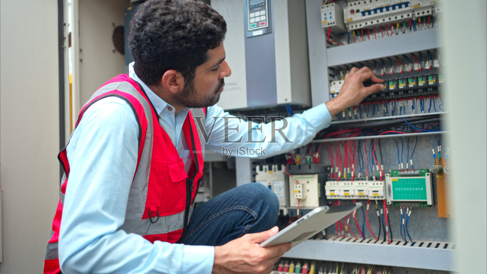 在工地使用起重机前，电气工程师检查起重机的电气控制板照片摄影图片