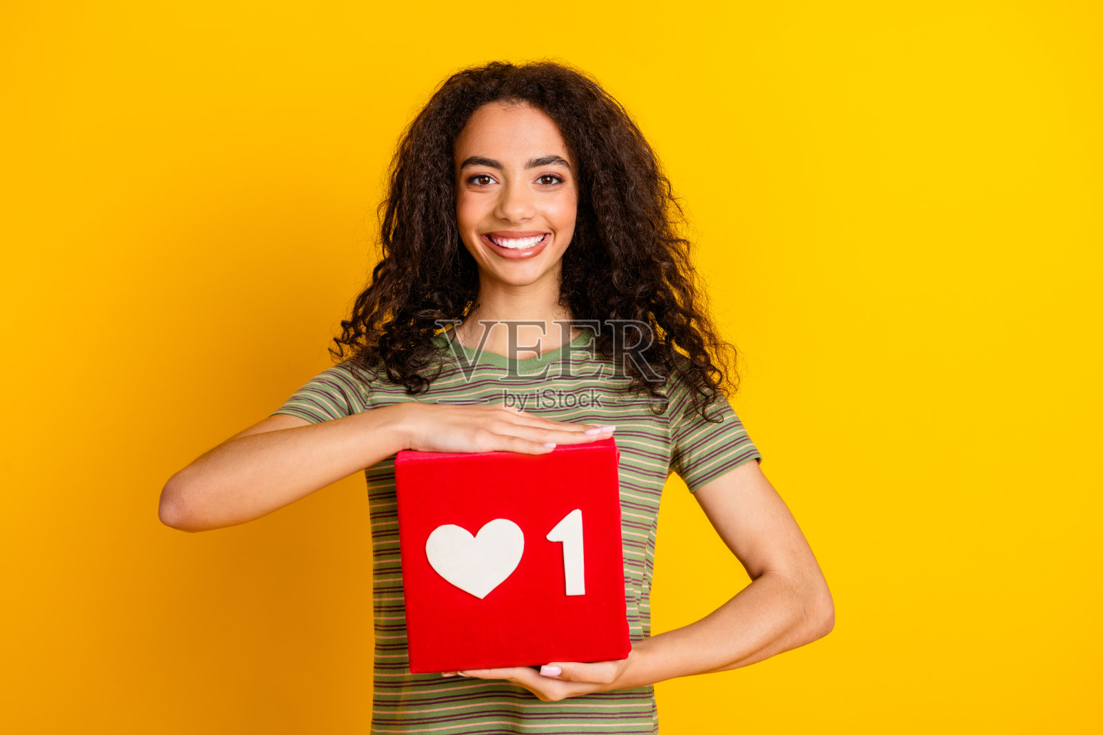 这张照片是一个很酷的积极向上的女孩，波浪发型，穿着t恤，在充满活力的黄色背景下，像抱在怀里一样拥抱着社交媒体照片摄影图片
