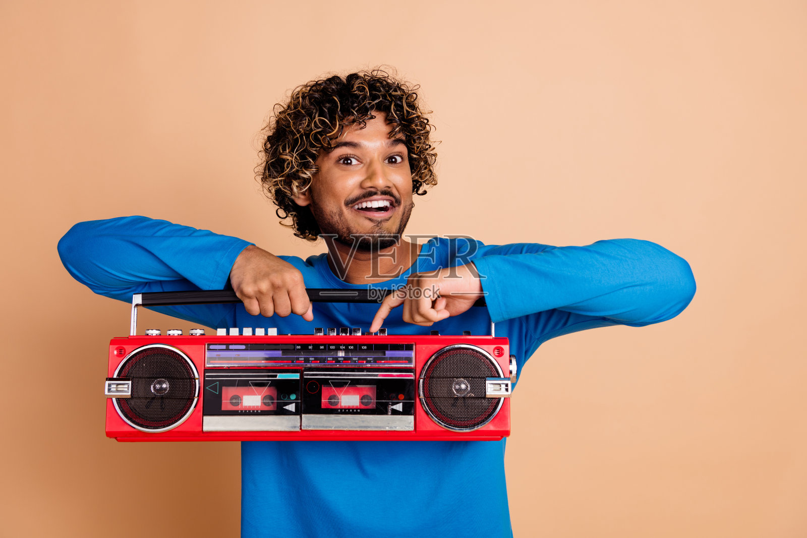 照片积极的无忧无虑的家伙穿着时尚的蓝色衣服，按钮打开孤立的米色背景照片摄影图片