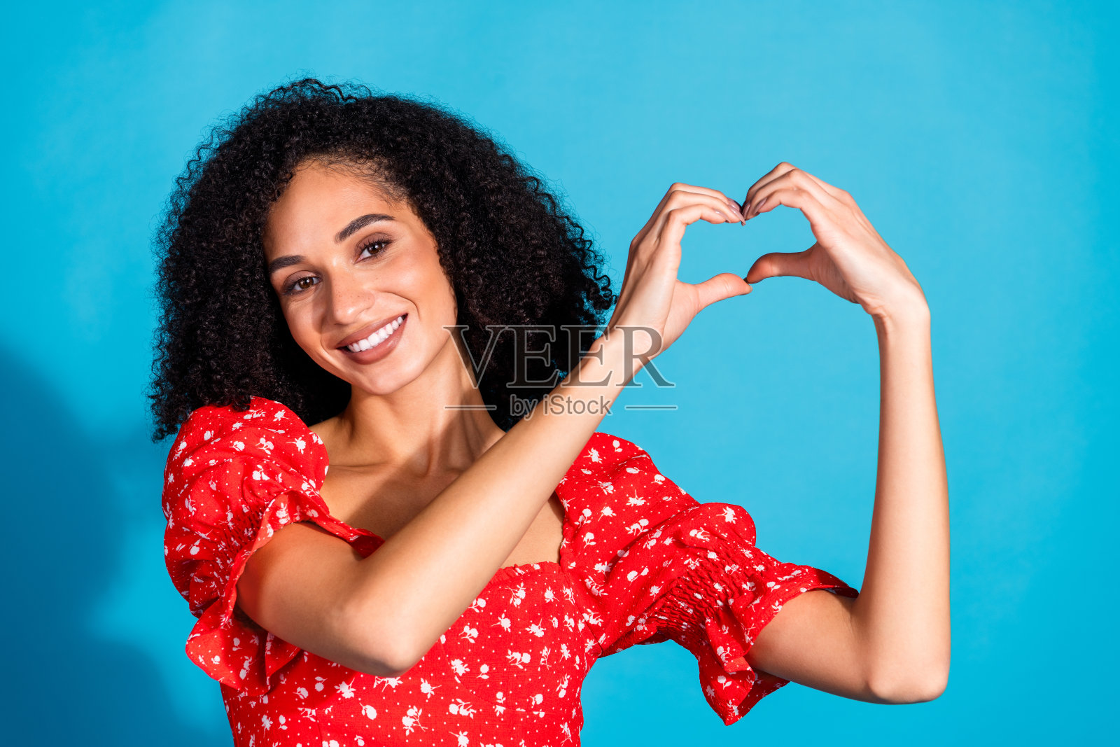 肖像的华丽的年轻女子显示心脏符号穿上衣孤立的蓝色背景照片摄影图片