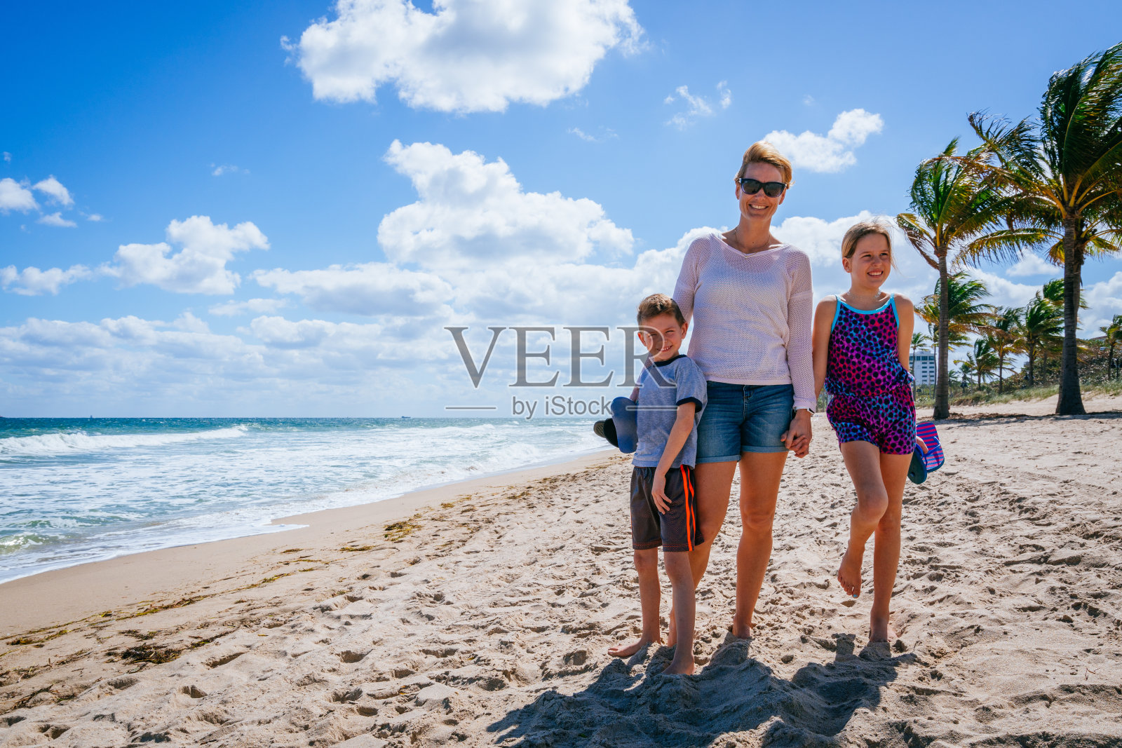 母亲带着孩子站在沙滩上照片摄影图片