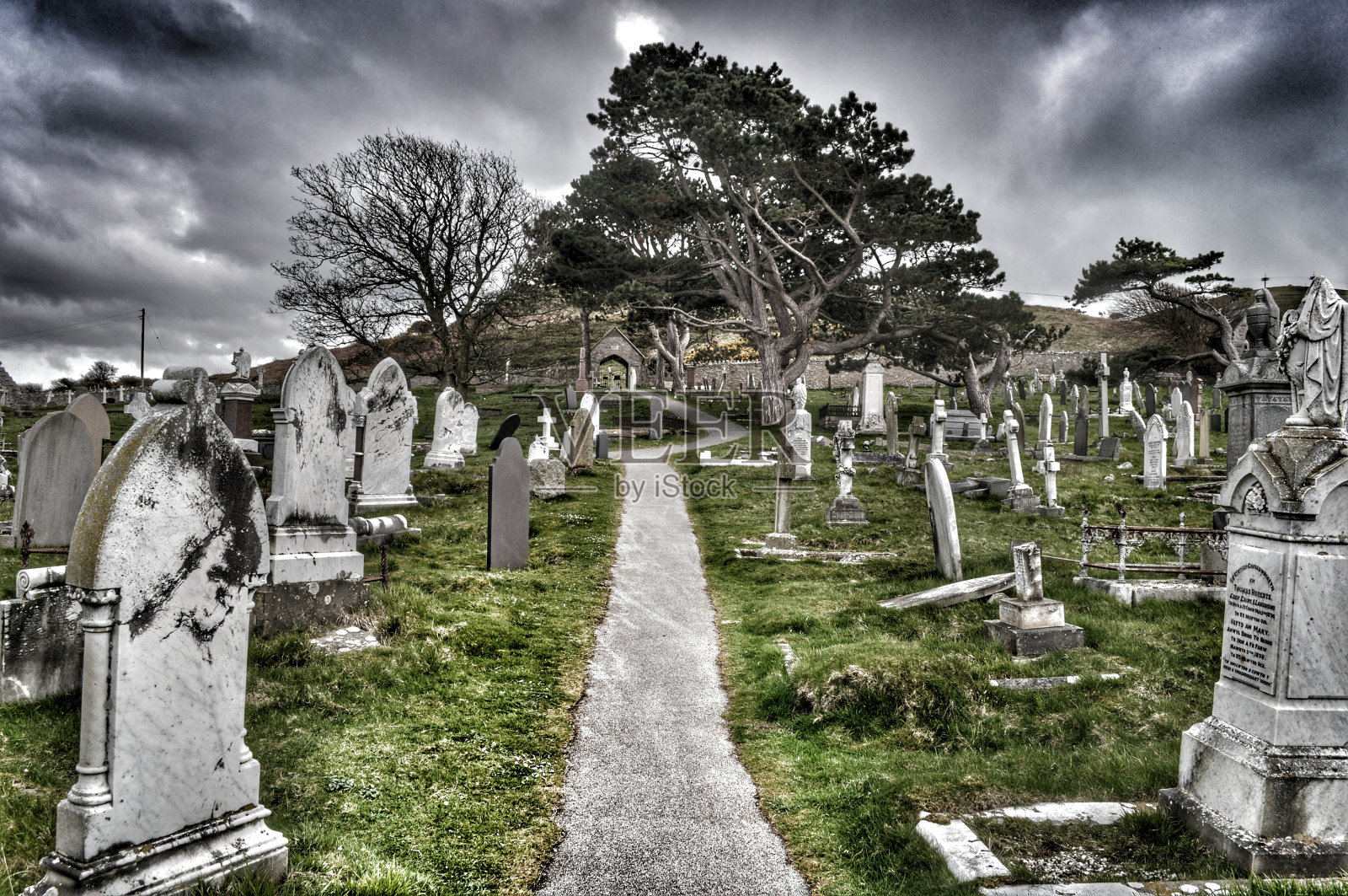 穿过墓地的小路，天空多云照片摄影图片