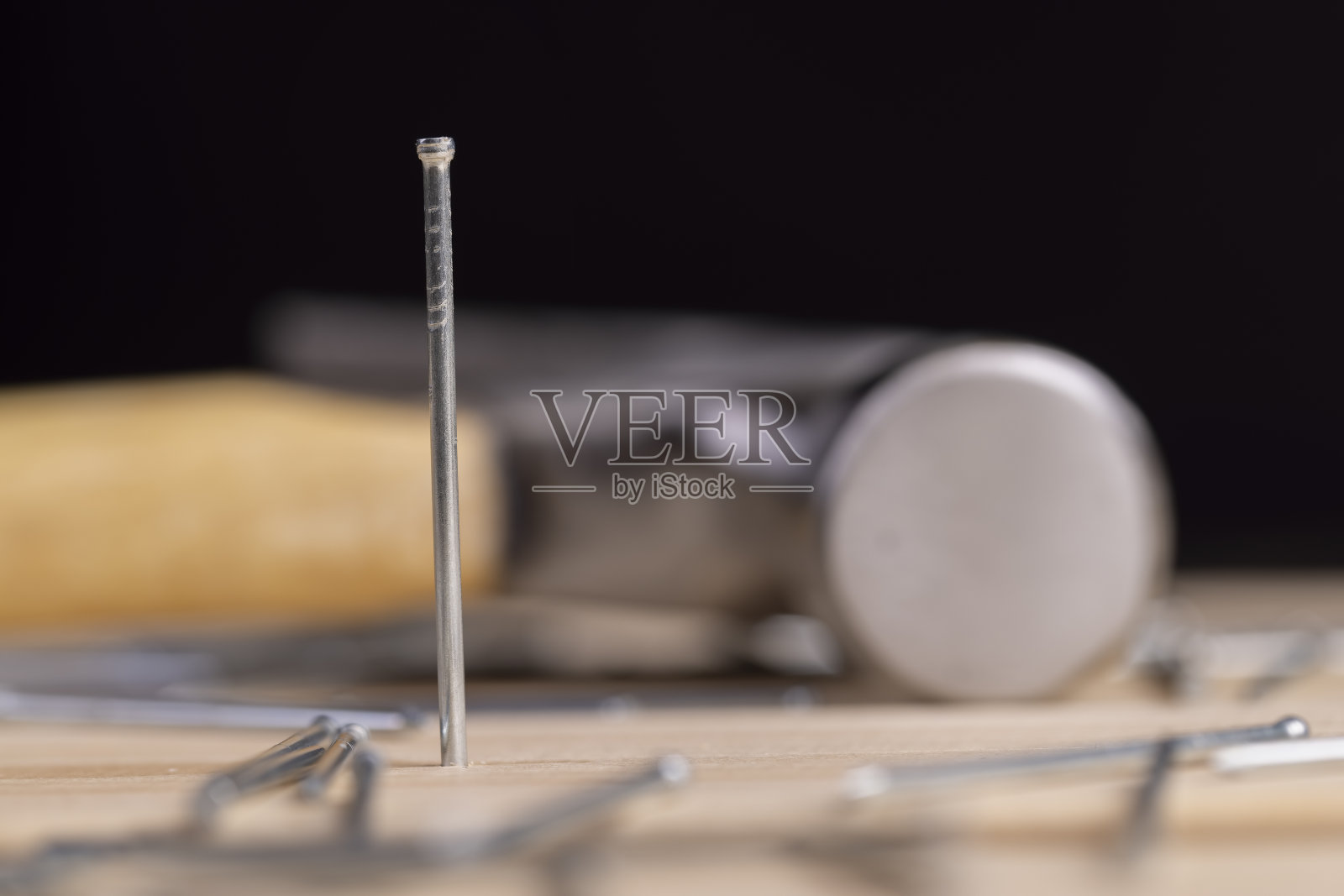带小帽的钉子和钉在木板上的铁锤照片摄影图片