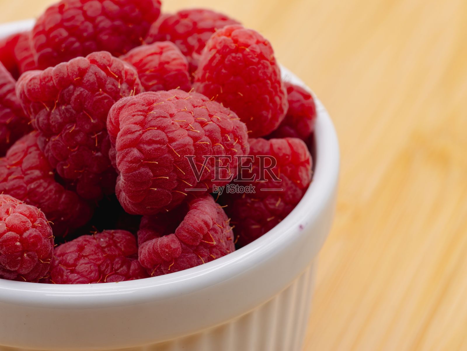 木桌背景上白色碗里的新鲜覆盆子特写照片摄影图片