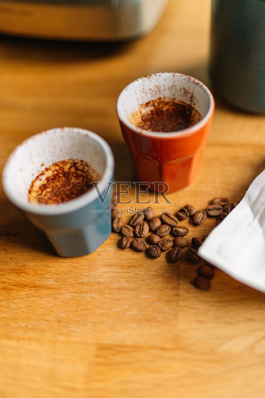 木桌上放着两个咖啡杯，里面装着咖啡豆照片摄影图片