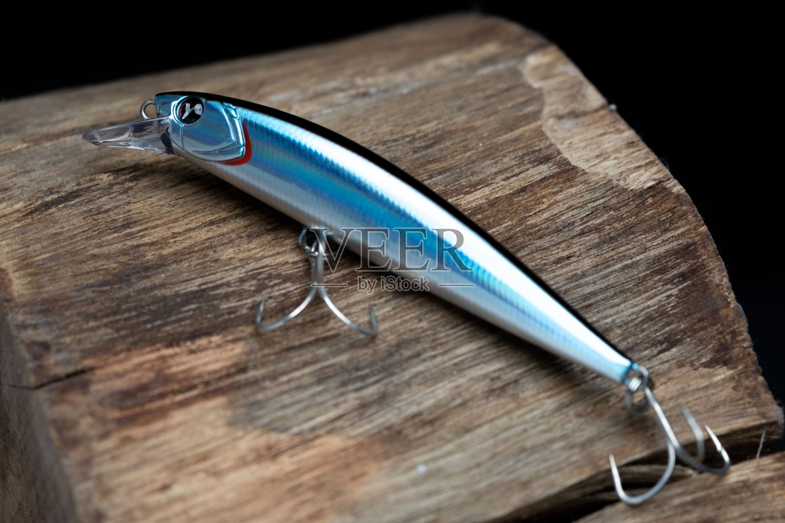 一个放置在木制表面上的闪亮鱼饵的特写，展示了细节和钩子。照片摄影图片