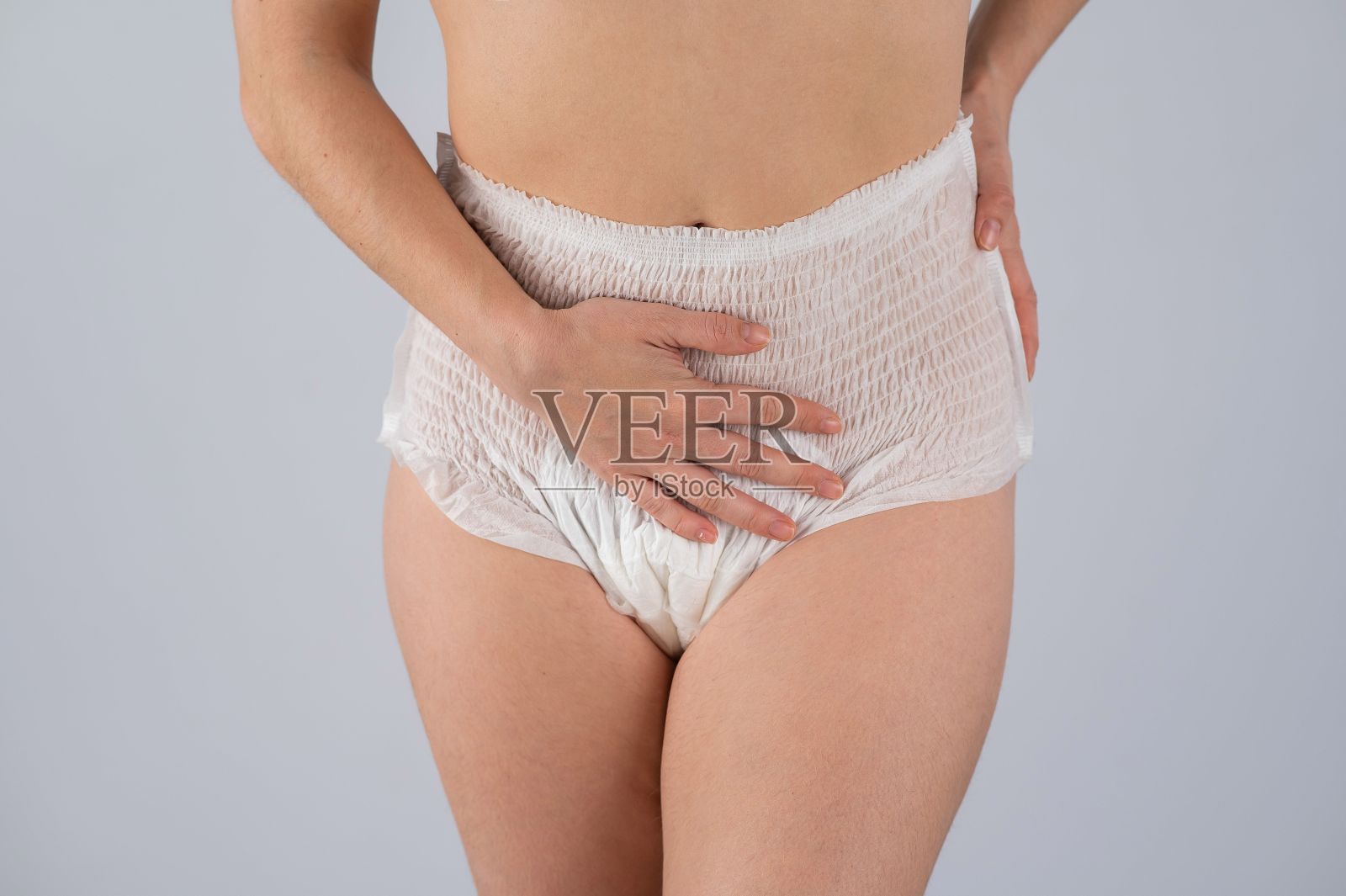 一个穿着成人尿布的女人把手放在肚子上。尿失禁问题。照片摄影图片