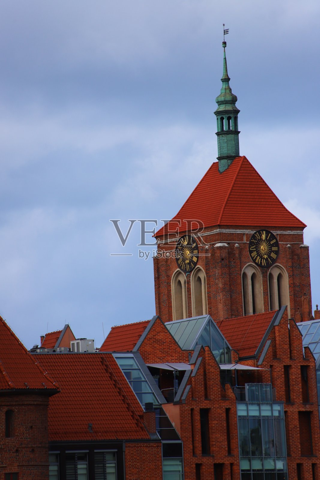 图为Gdańsk圣约翰教堂的塔楼，塔楼上有钟，还有几栋廉租房屋的屋顶照片摄影图片