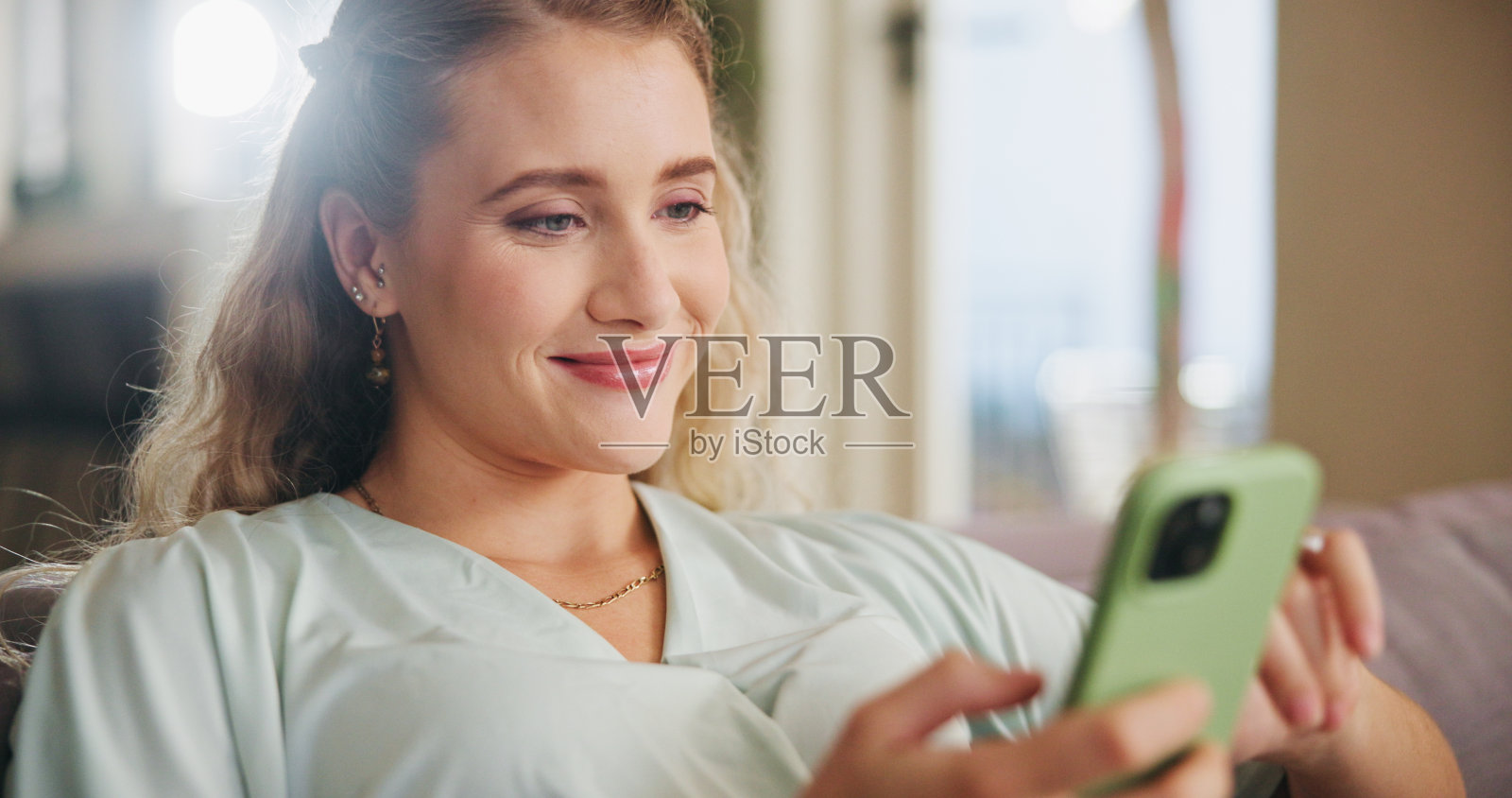 沙发，微笑和女人用智能手机滚动，聊天和短信与在线联系人的计划。家，女性和手机与约会网站聊天，匹配伴侣或移动应用程序照片摄影图片