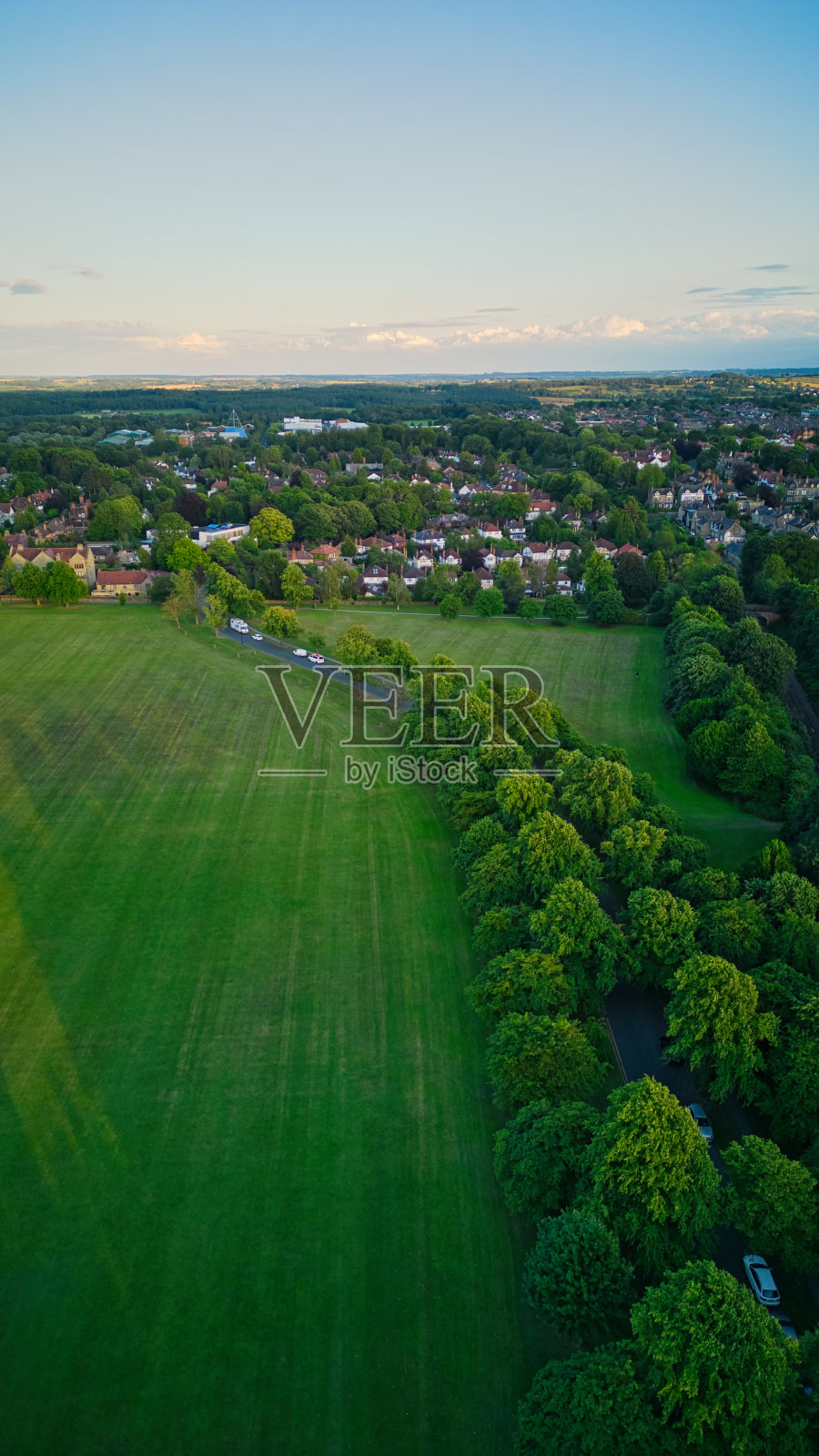 在晴朗的黄昏，北约克郡的哈罗盖特，鸟瞰一片郁郁葱葱的绿色田野，通往有房屋和树木的郊区。照片摄影图片