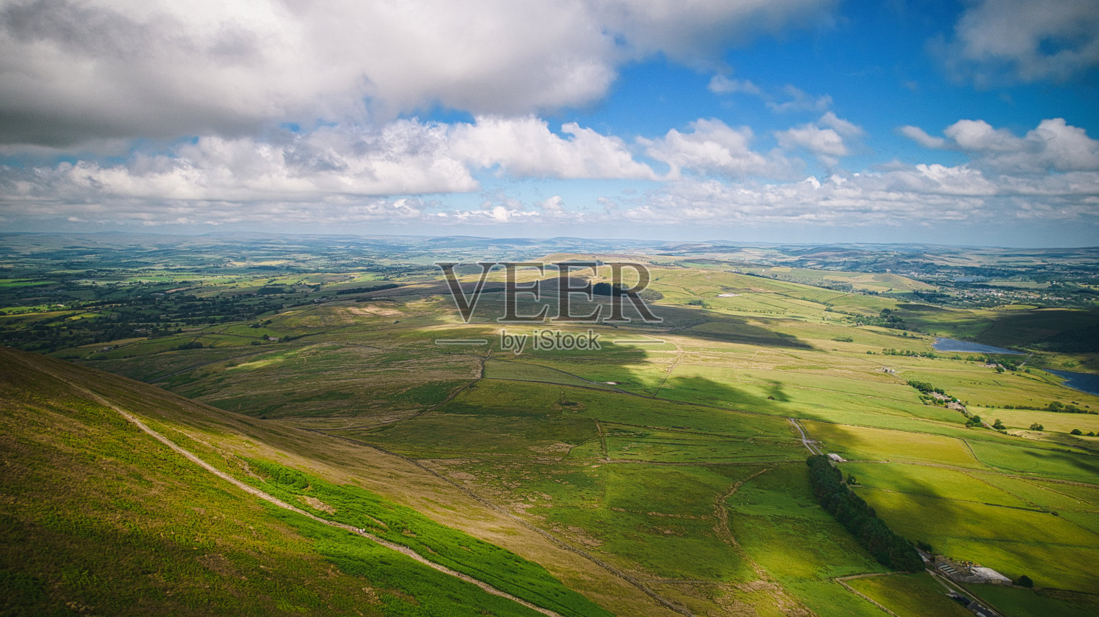 鸟瞰郁郁葱葱的绿色乡村，连绵起伏的山丘和散落的云在英国彭德尔山的景观上投下阴影。照片摄影图片