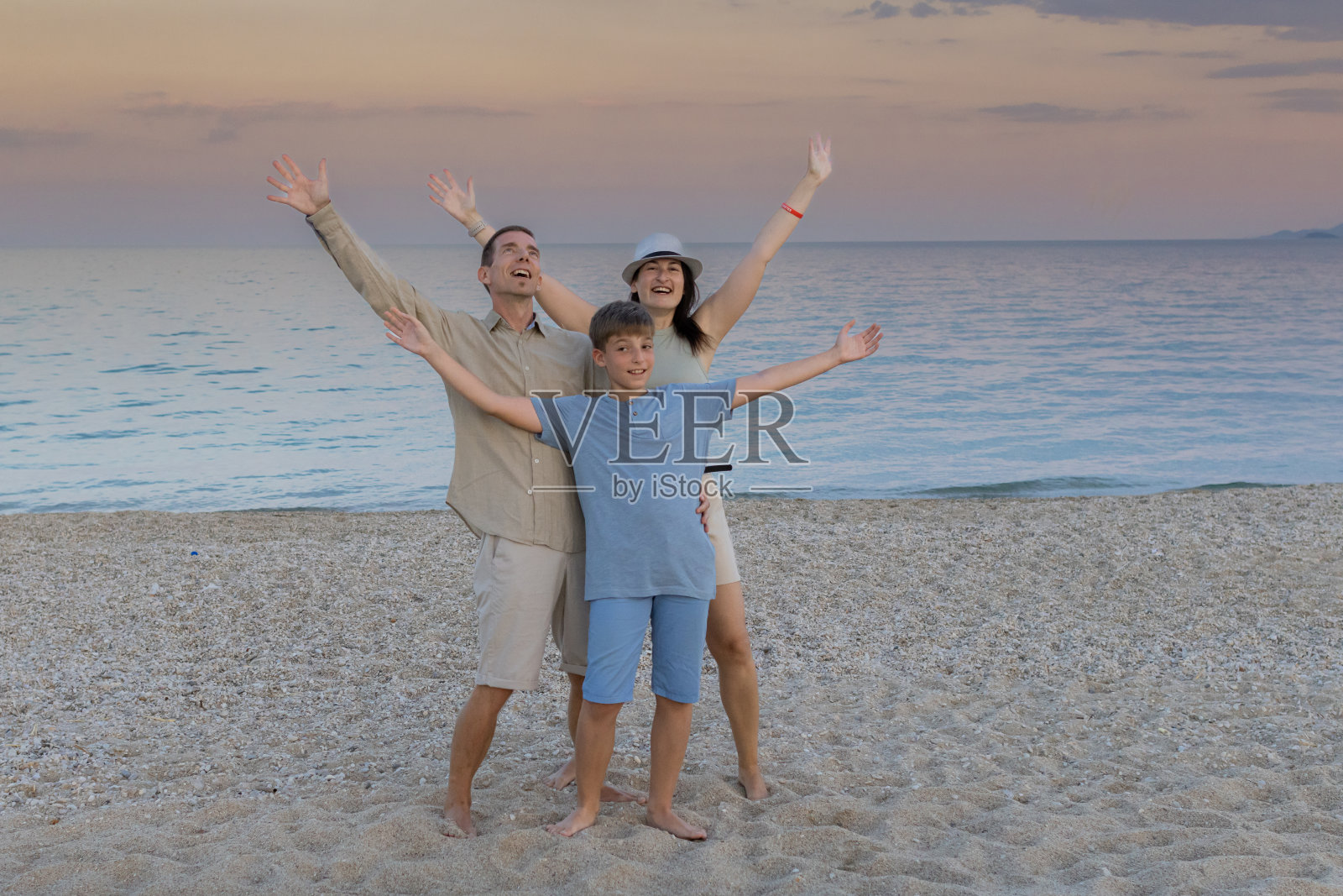 幸福，快乐的家庭和一个孩子享受黄昏时分在海边的海滩上度过的时光。高质量的家庭度假时间。一起享受夏日冒险的珍贵时刻。照片摄影图片