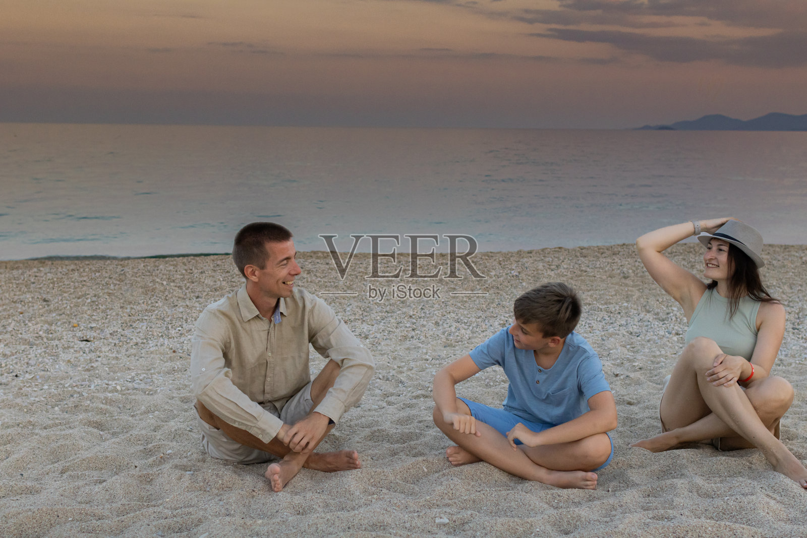 幸福，快乐的家庭和一个孩子享受黄昏时分在海边的海滩上度过的时光。高质量的家庭度假时间。一起享受夏日冒险的珍贵时刻。照片摄影图片