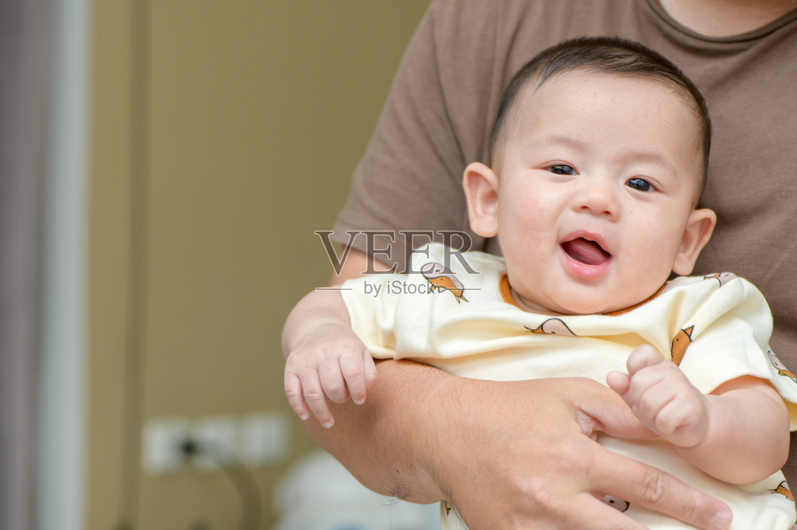 可爱的亚洲欢快的婴儿微笑在母亲的手中。情感婴儿概念照片摄影图片