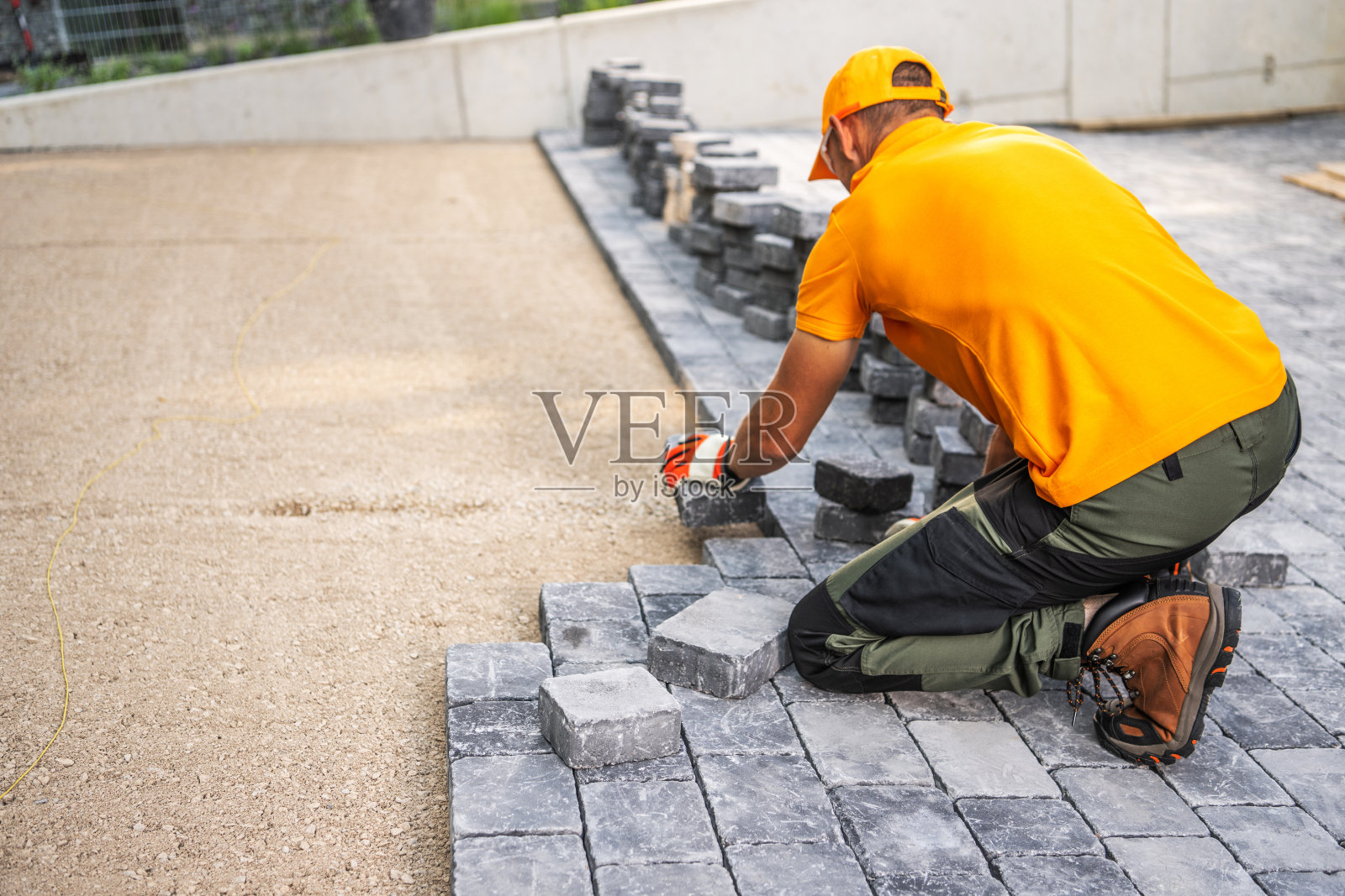 在一个阳光明媚的日子里，工人在住宅后院铺设鹅卵石照片摄影图片