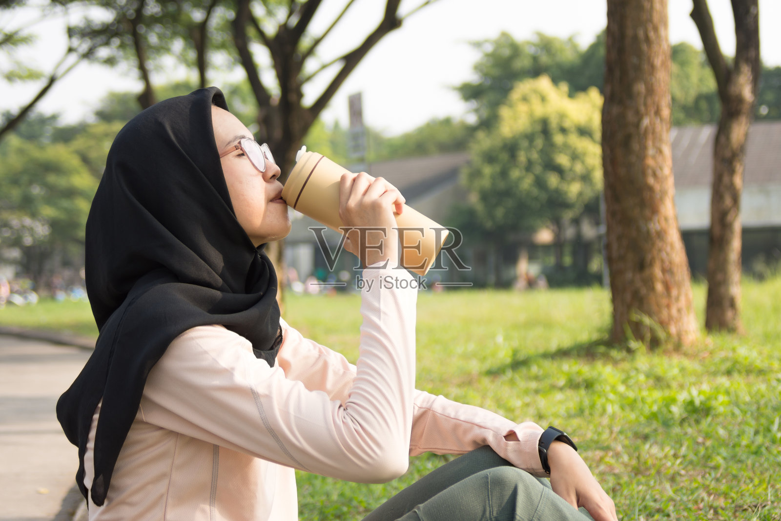 疲惫的亚洲女运动员正在休息，用可重复使用的旅行杯喝水照片摄影图片