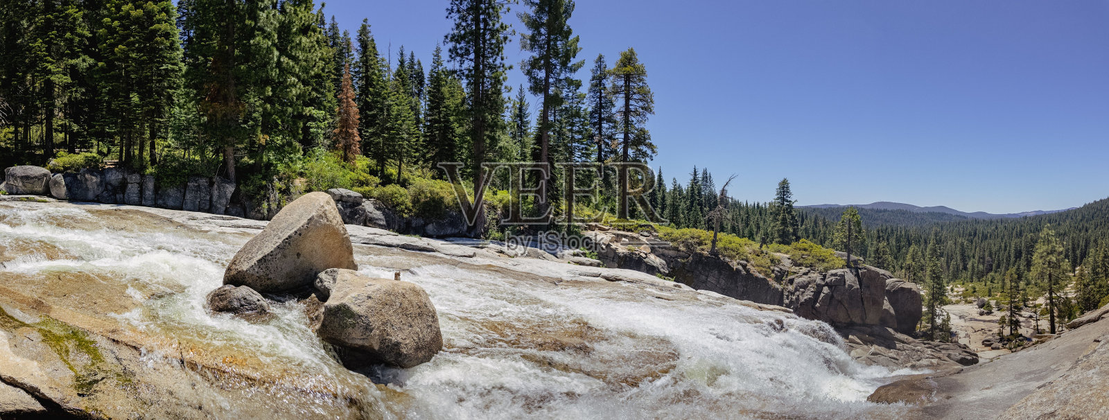 在清澈的蓝天下，一条岩石河流流经森林地区照片摄影图片