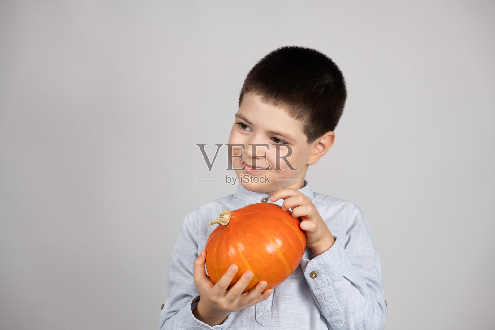可爱快乐的孩子与小北海道南瓜在白色的背景。照片摄影图片