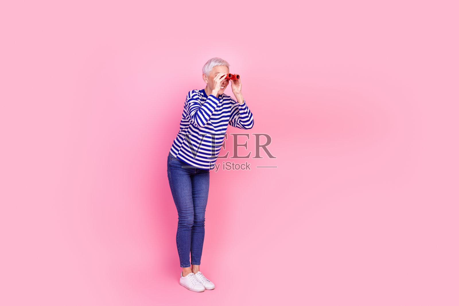照片中迷人可爱开朗的高级女子穿着条纹时髦的衣服，在粉红色的背景上显得空旷孤立照片摄影图片