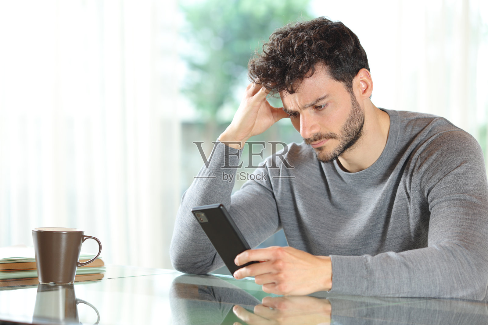 忧心忡忡的男子在家查看手机照片摄影图片