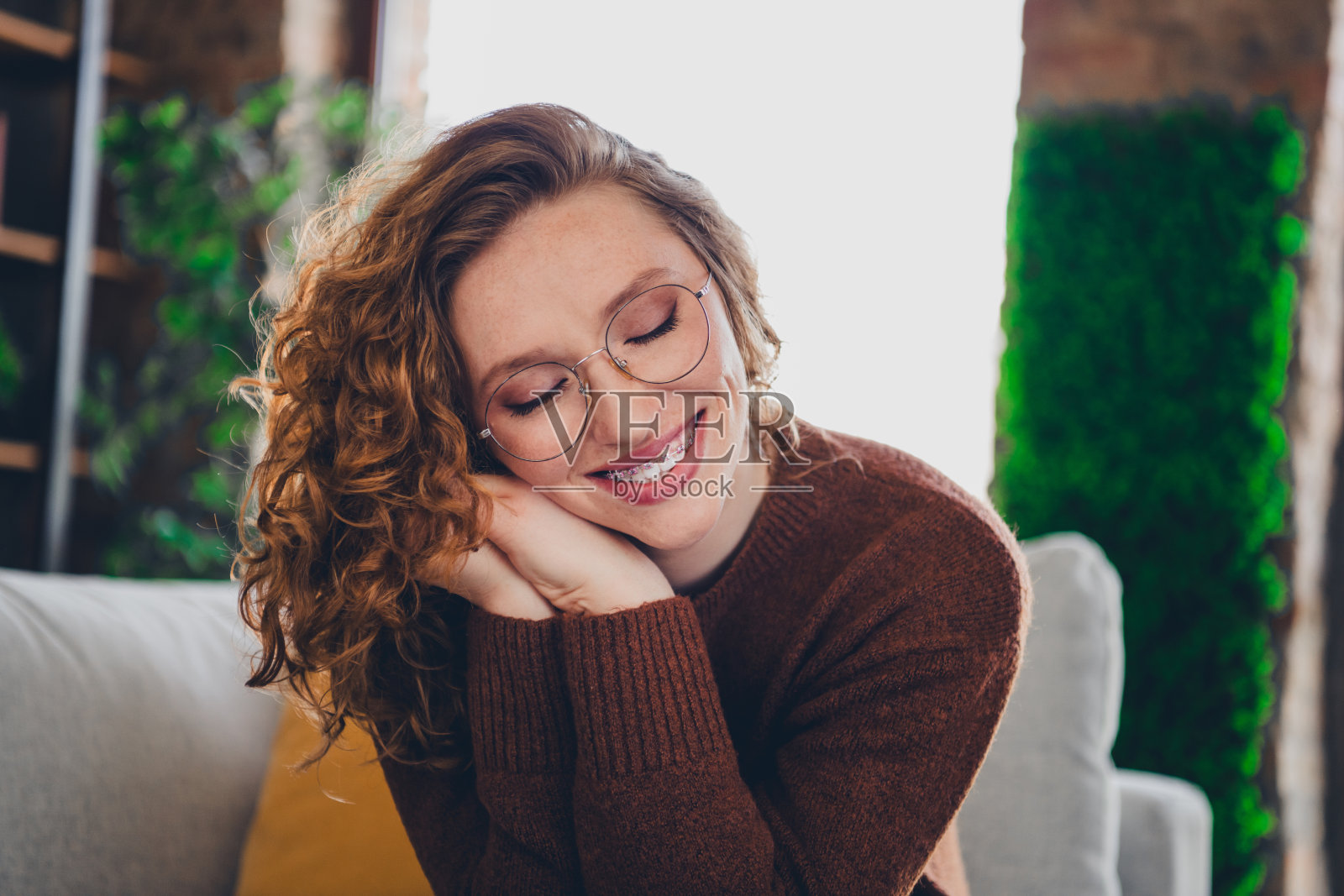 照片开朗可爱可爱的可爱的女人穿着时尚的套头衫，手摸脸在室内的房子照片摄影图片