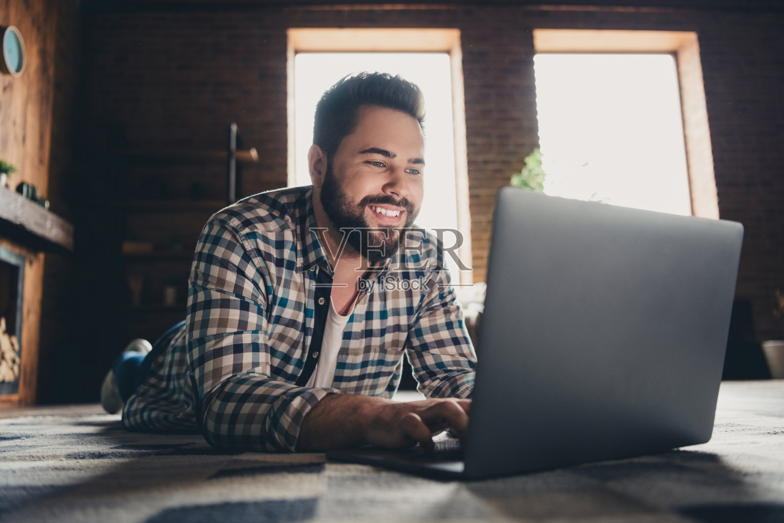 有吸引力的时髦开朗的年轻人花时间躺在地板上上网本电子商务移动新公寓，家庭室内室内照片摄影图片