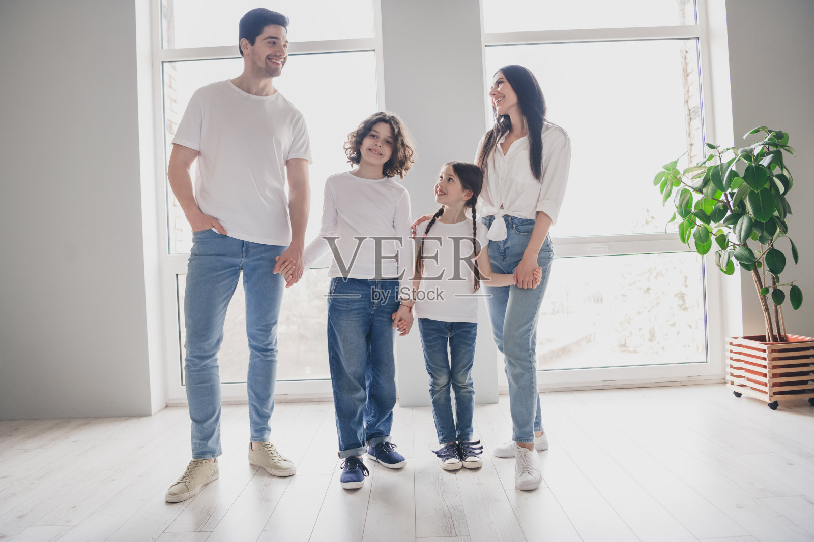 照片中漂亮可爱的孩子们，爸爸妈妈穿着休闲服，挽着胳膊在室内的房子公寓房间里照片摄影图片