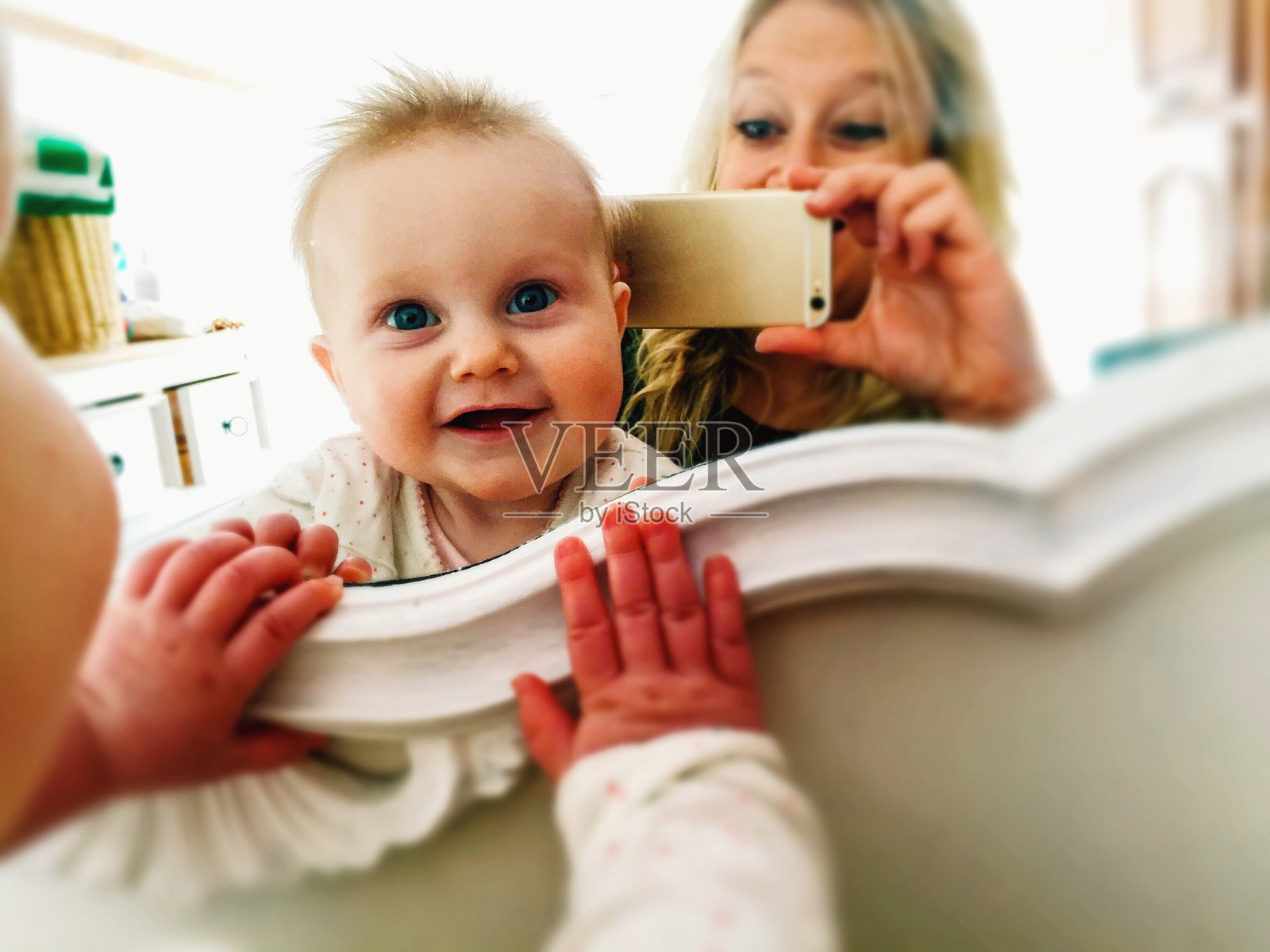 可爱的宝宝和妈妈在镜子前拍照的肖像照片摄影图片