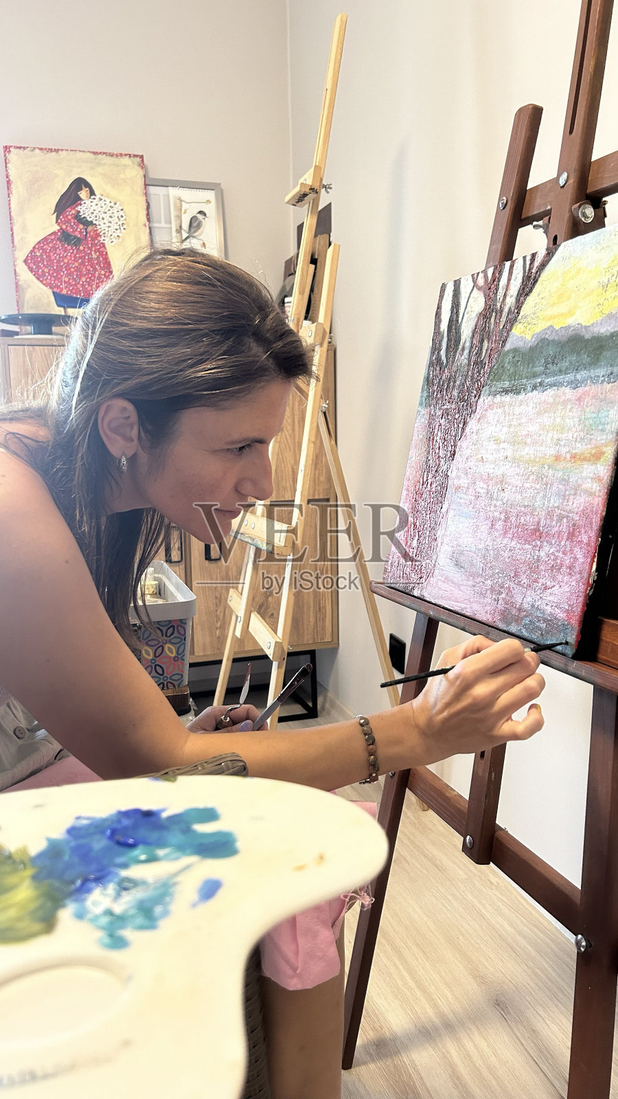 一位女画家用颜料和画笔在画布上作画的特写照片摄影图片