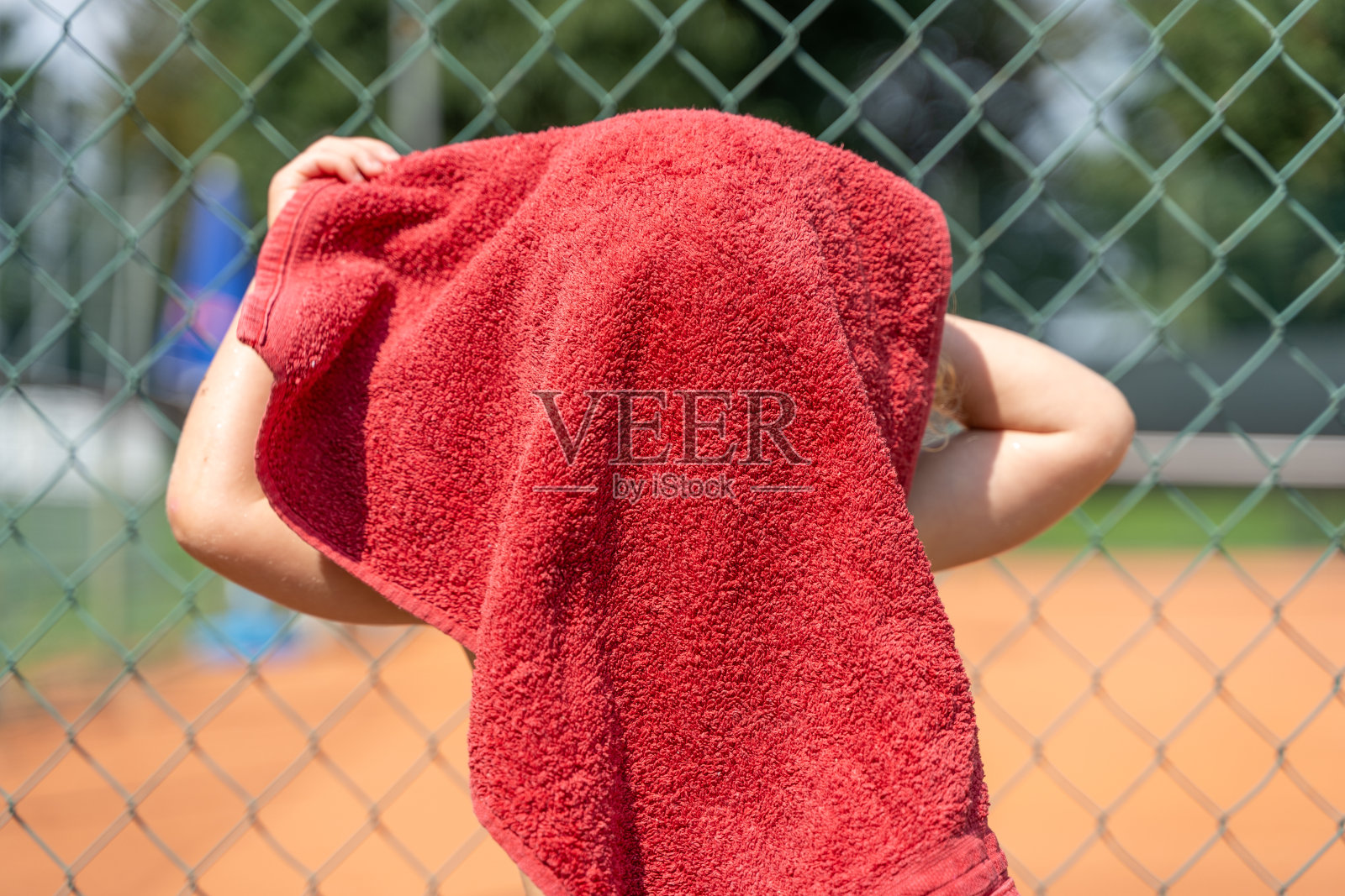 漂亮的肖像，一个2岁的卷发金发女孩玩着一条红毛巾照片摄影图片