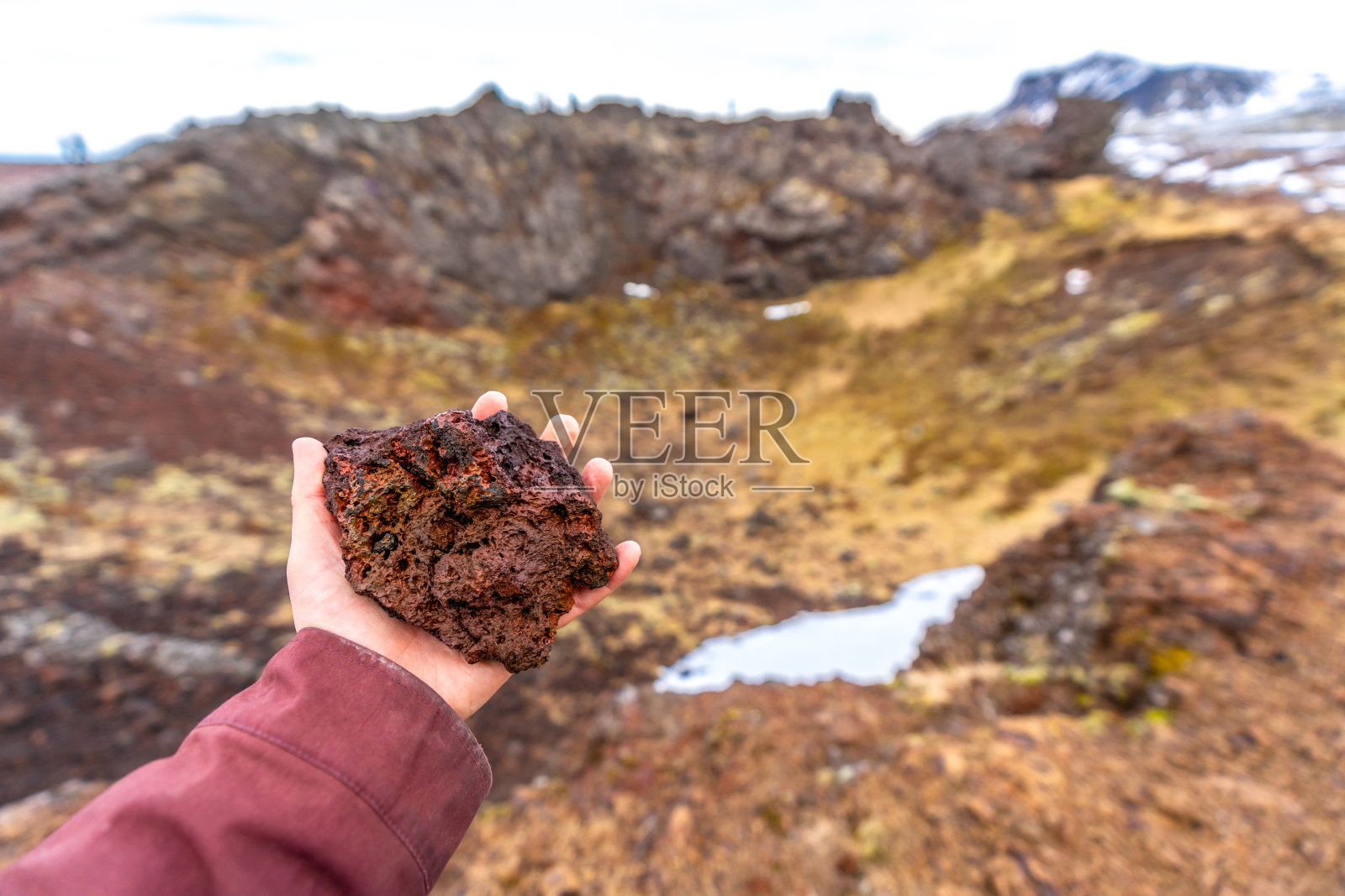 在冰岛斯奈费尔斯半岛的萨克斯霍尔火山口，拿着红色的火山岩照片摄影图片