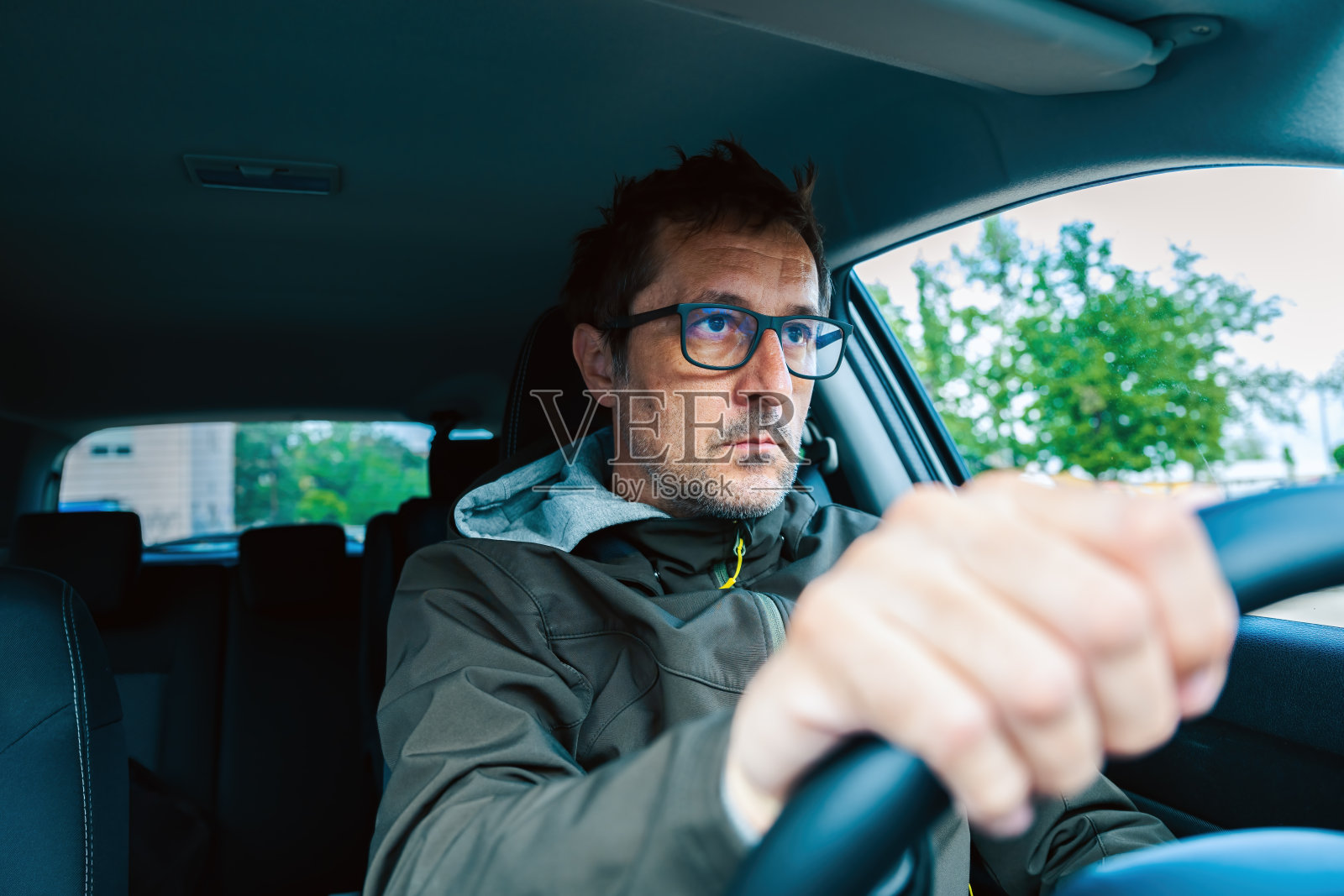 谨慎的司机戴着眼镜，一边开车一边仔细观察前方的道路照片摄影图片