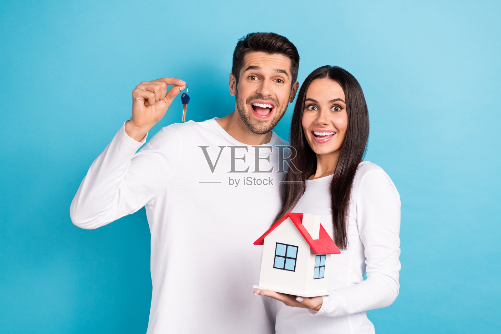 照片肖像漂亮的年轻男子女孩小房子钥匙兴奋开朗穿着时尚的白色衣服孤立在蓝色的背景照片摄影图片