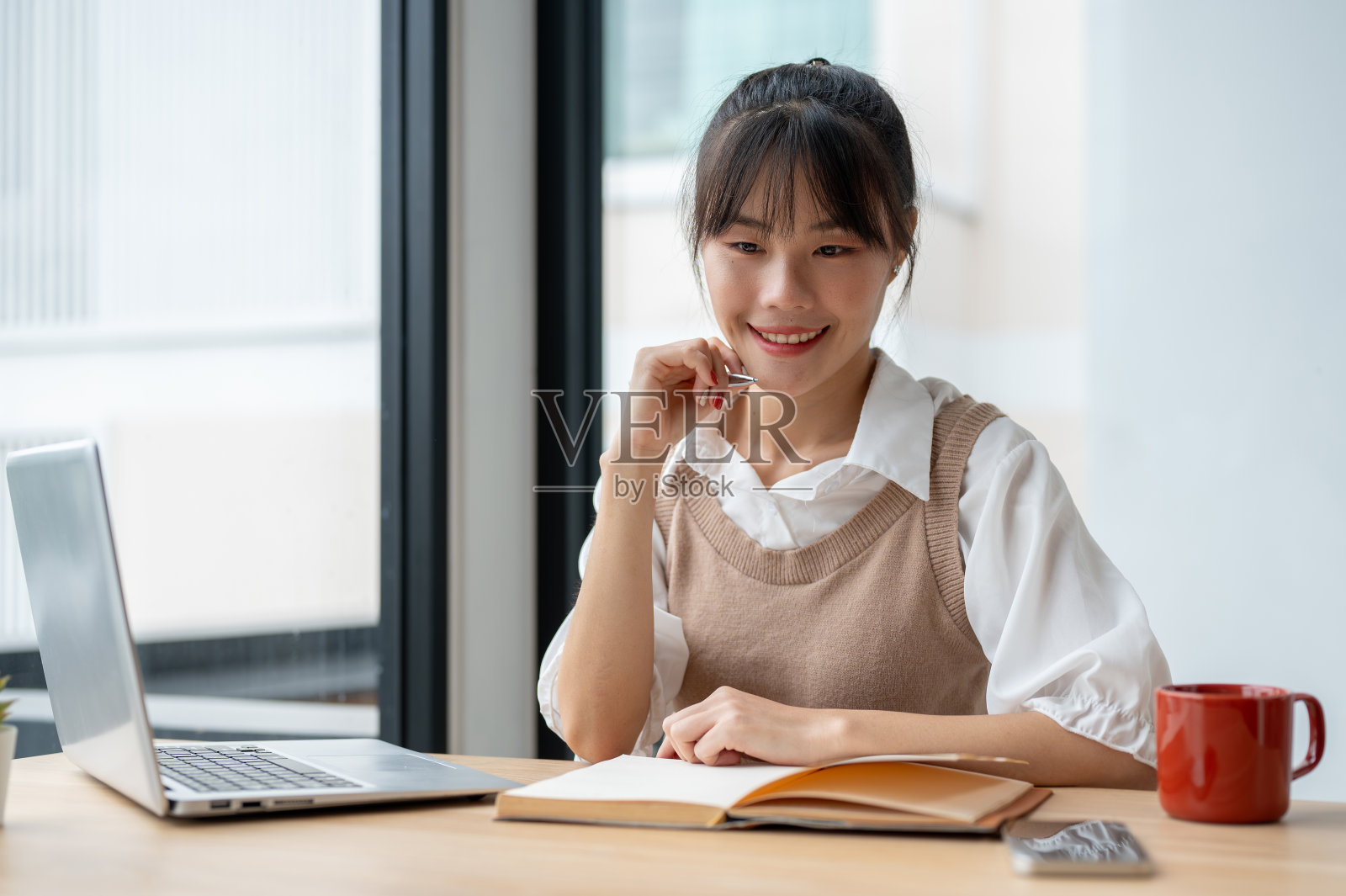 一个美丽的亚洲女人在做白日梦，在办公室工作的时候想一些事情。照片摄影图片