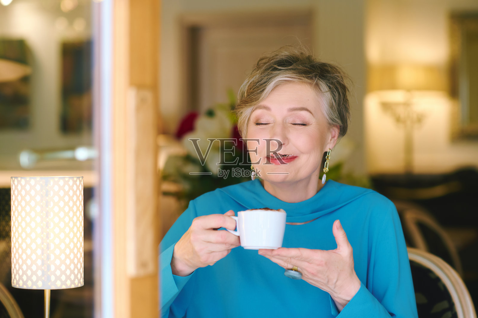 优雅的55 - 60岁老妇人在舒适的咖啡馆里享受咖啡的肖像照片摄影图片
