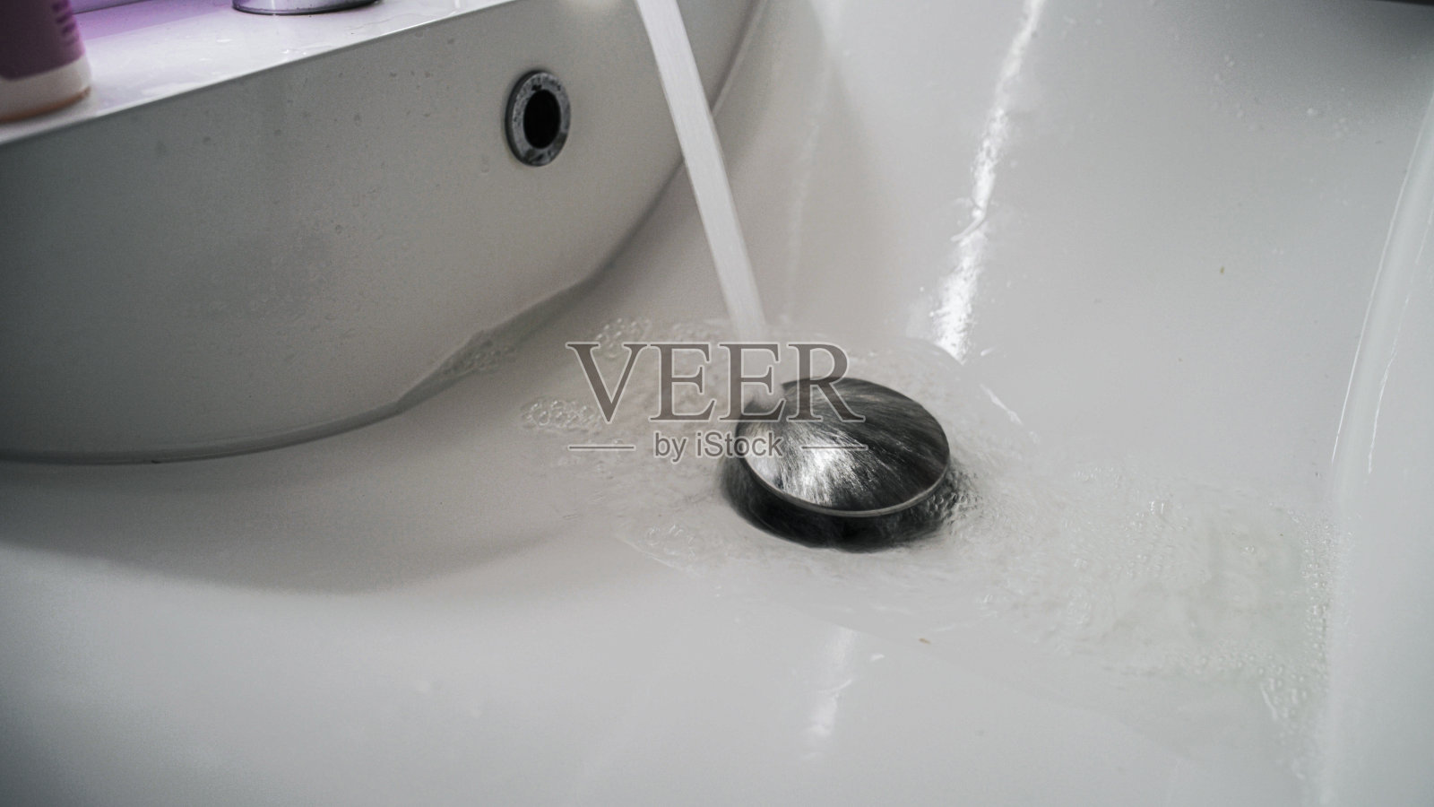 清洁浴室水槽，用水倒在镀铬塞子上照片摄影图片