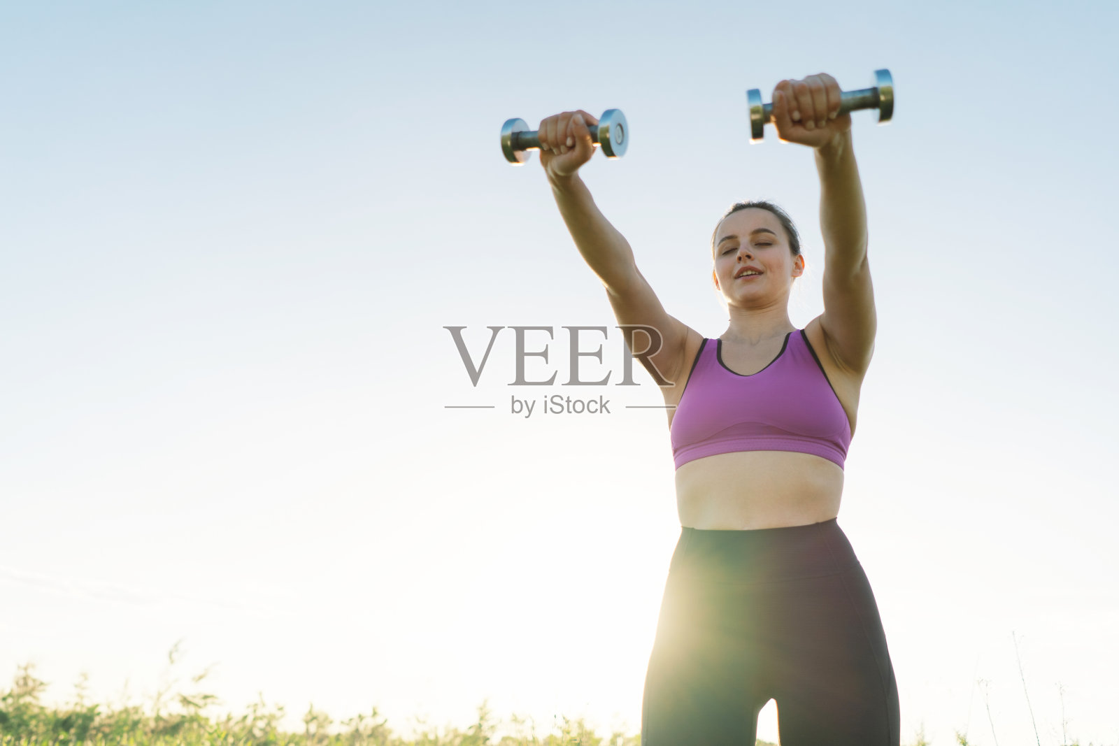 一个女孩在阳光明媚的夏日夕阳下在大自然中健身或做瑜伽照片摄影图片