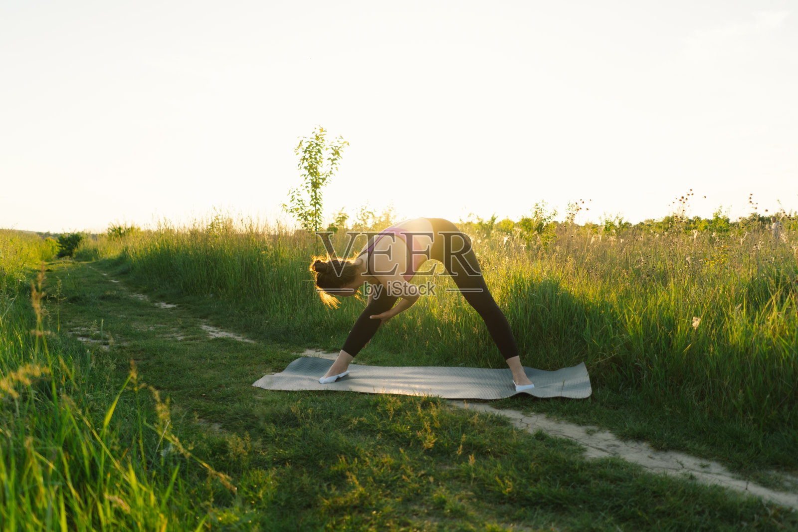 一个女孩在阳光明媚的夏日夕阳下在大自然中健身或做瑜伽照片摄影图片