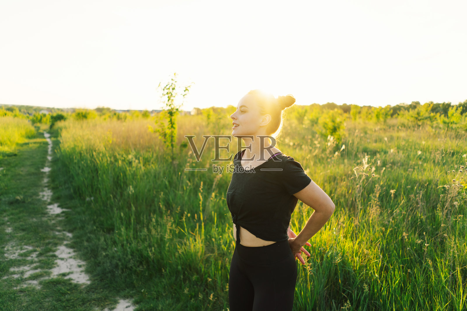 一个女孩在阳光明媚的夏日夕阳下在大自然中健身或做瑜伽照片摄影图片