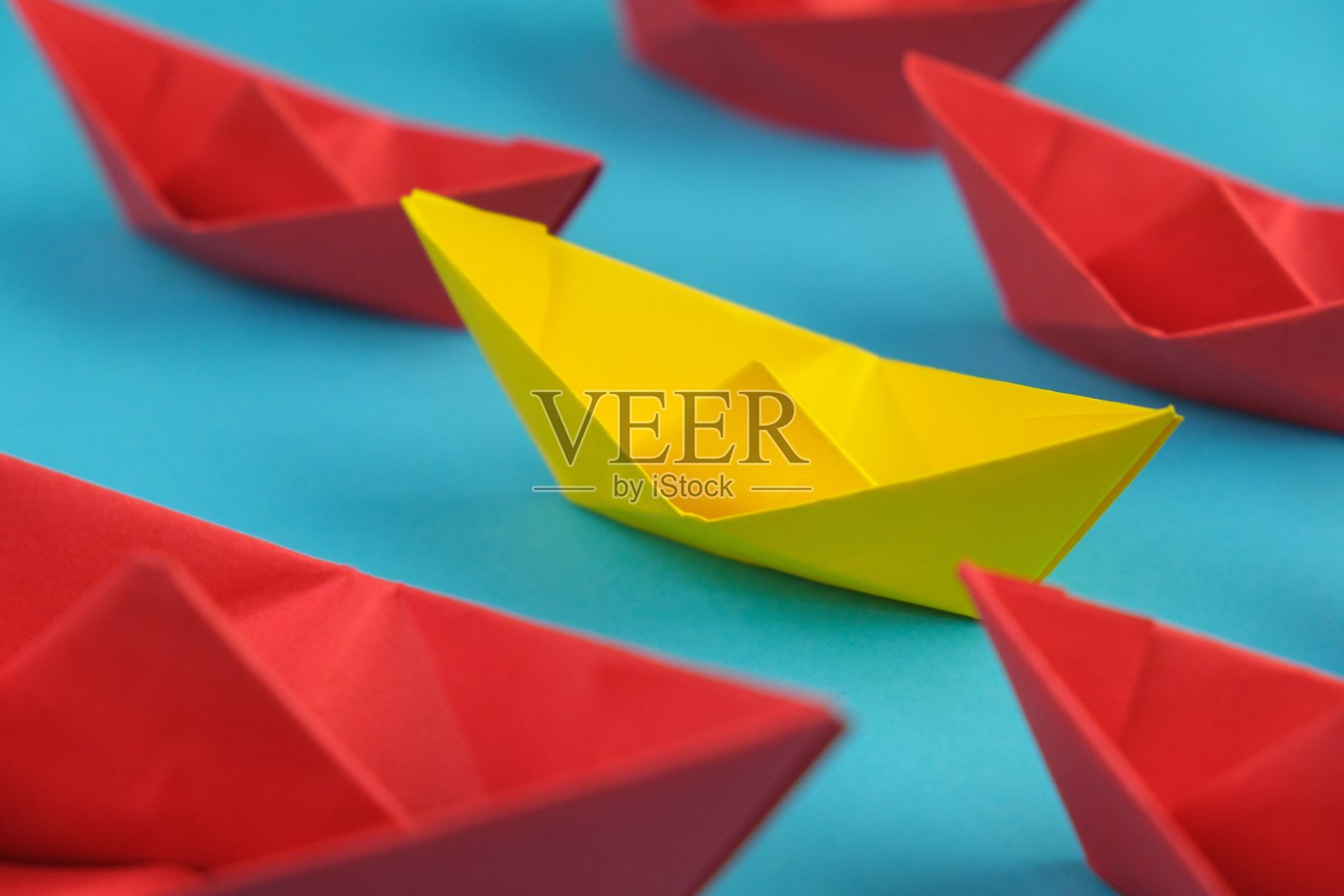 红纸船在蓝色的水面上领先于其他黄纸船。平铺以留出文字空间。独特的概念。成功，领导概念照片摄影图片