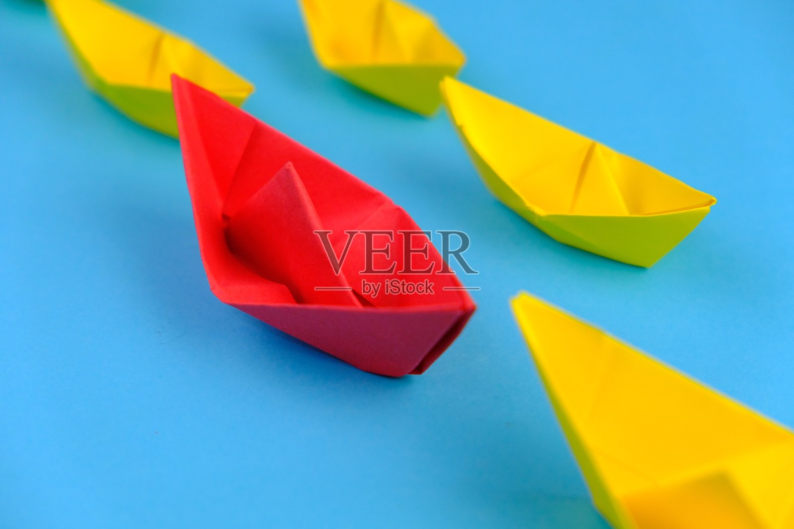 红纸船在蓝色的水面上领先于其他黄纸船。平铺以留出文字空间。独特的概念。成功，领导概念照片摄影图片