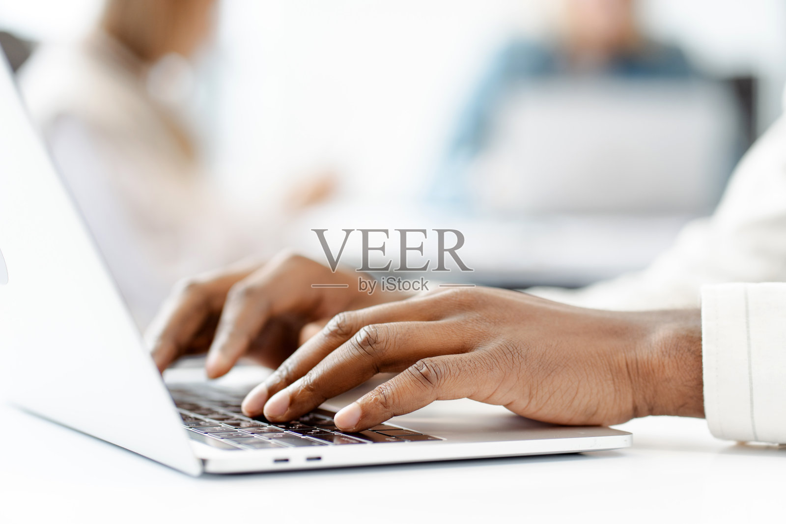 经理在繁忙的办公室里，在笔记本电脑键盘上打字，选择性地集中在手上照片摄影图片