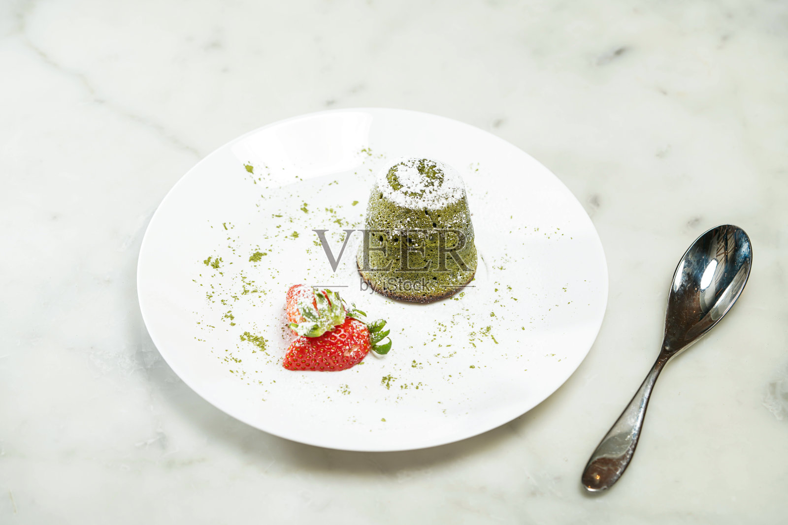 融化的抹茶绿色巧克力熔岩蛋糕被放在盘子里，孤立在灰色的背景上，亚洲烘焙咖啡馆甜点的顶部视图照片摄影图片