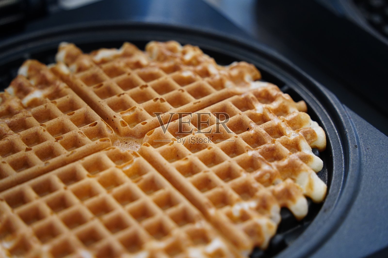 比利时华夫饼放在厨房桌子上的煎锅里。照片摄影图片