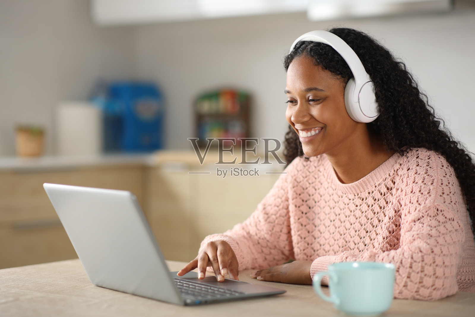 黑人女性在厨房里用笔记本电脑和耳机照片摄影图片