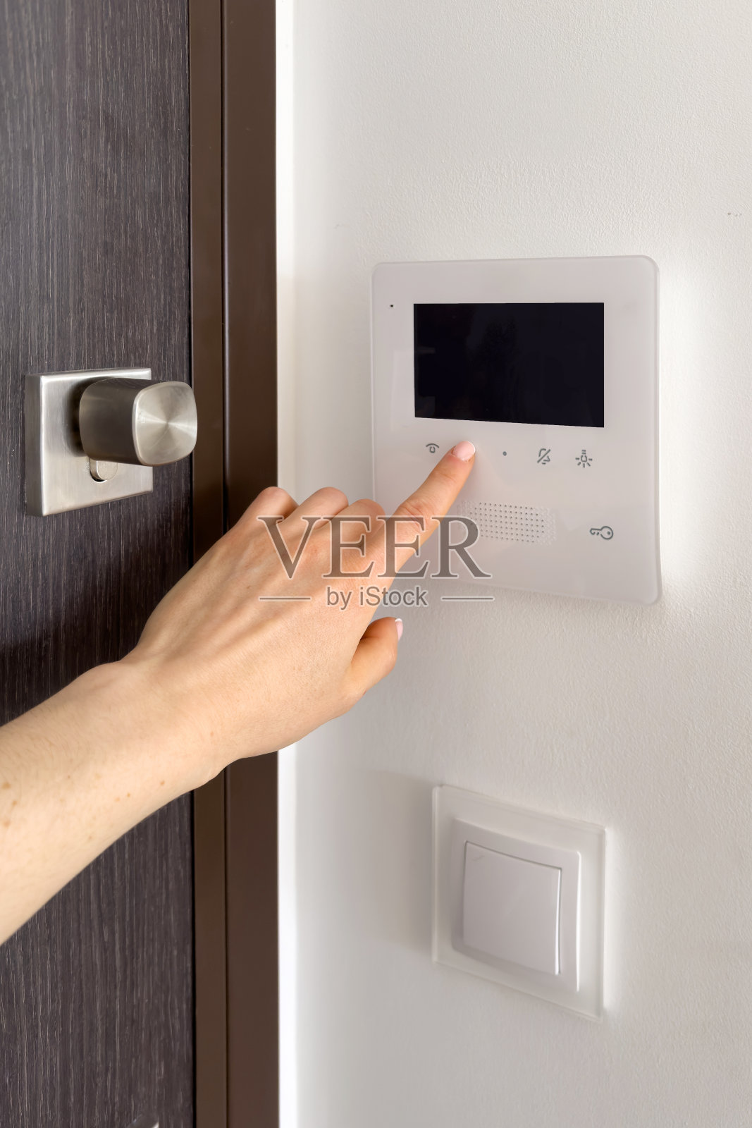 女士用手按下对讲系统的按钮，打开前门照片摄影图片