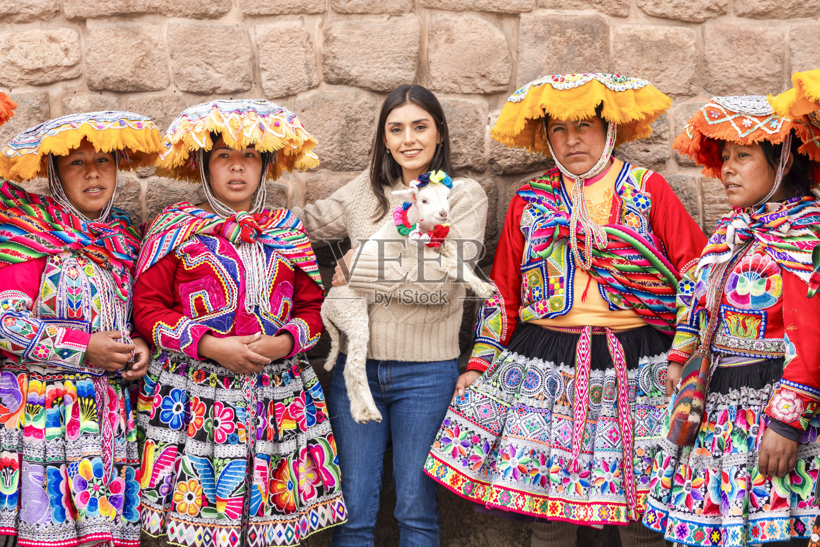 游客在库斯科与土著妇女合影，她们穿着漂亮的彩色衣服，展示小羊羔，拍照收费几枚硬币。照片摄影图片